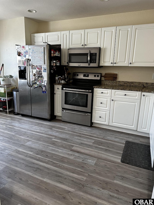 kitchen featuring a textured ceiling, stainless steel appliances, dark wood-type flooring, and white cabinetry