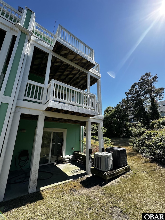 rear view of house featuring central air condition unit, a patio area, and a lawn