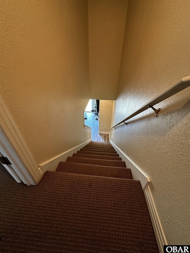 staircase featuring a textured wall