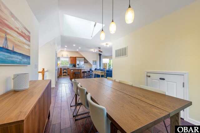 dining room with vaulted ceiling with skylight, baseboards, visible vents, dark wood-style flooring, and recessed lighting