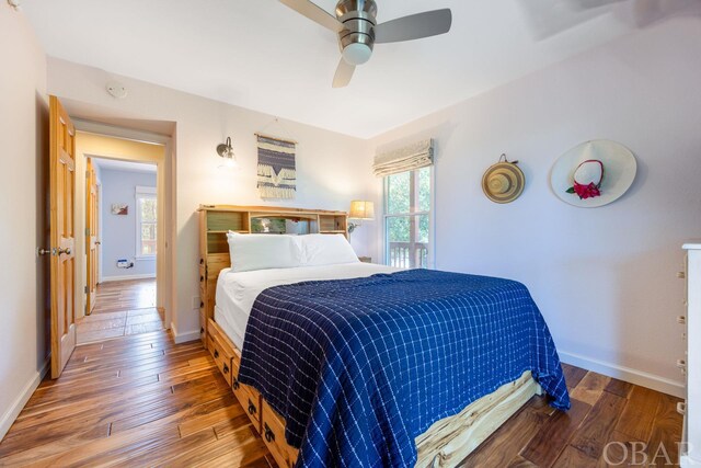 bedroom with multiple windows, wood finished floors, a ceiling fan, and baseboards