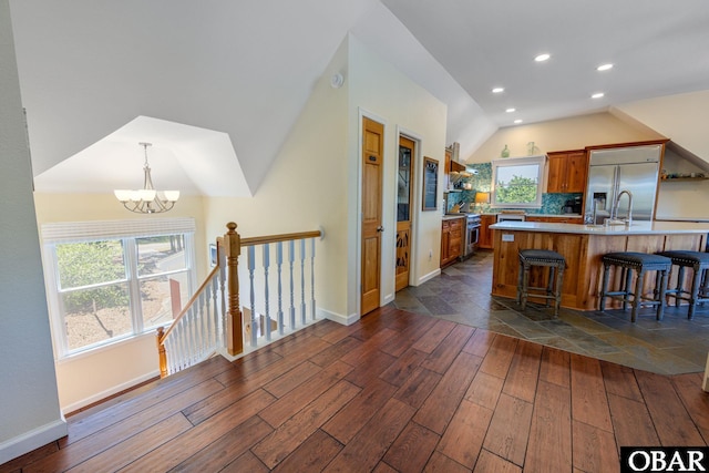 kitchen featuring lofted ceiling, a breakfast bar area, light countertops, appliances with stainless steel finishes, and dark wood finished floors