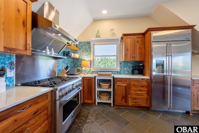 kitchen featuring extractor fan, light stone countertops, backsplash, brown cabinets, and high end appliances