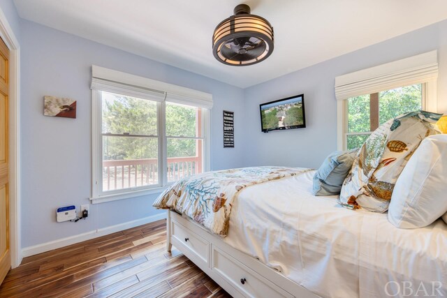 bedroom with multiple windows, wood finished floors, and baseboards