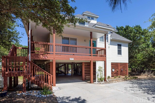 view of front of house featuring a shingled roof, concrete driveway, stairway, a porch, and a carport