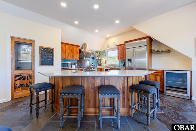 kitchen with wine cooler, stone tile flooring, light countertops, appliances with stainless steel finishes, and extractor fan