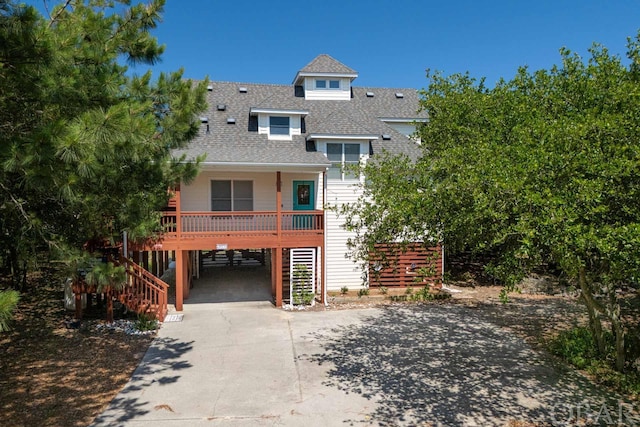 view of front of property with a shingled roof, concrete driveway, stairway, a porch, and a carport