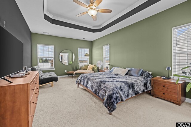 bedroom with carpet flooring, a ceiling fan, visible vents, baseboards, and a tray ceiling