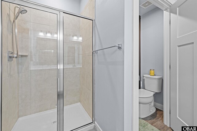 full bath with toilet, wood finished floors, visible vents, baseboards, and a shower stall