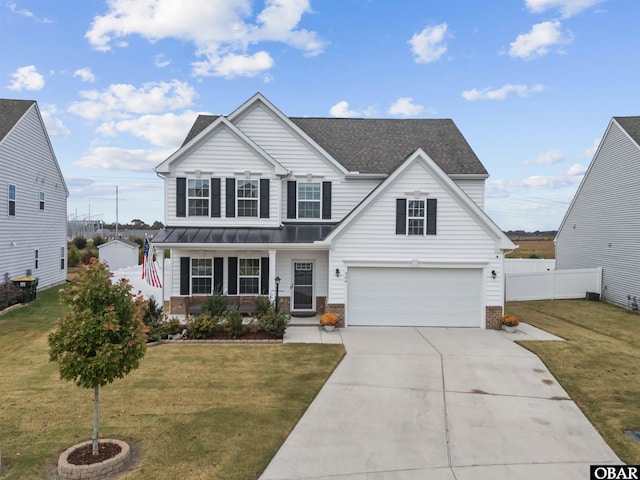 traditional home with an attached garage, fence, driveway, a standing seam roof, and a front yard