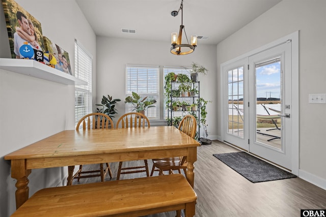 dining space featuring light wood-style flooring, visible vents, a chandelier, and baseboards