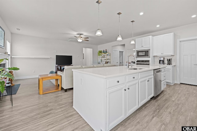 kitchen featuring black microwave, light wood finished floors, a sink, and white cabinets