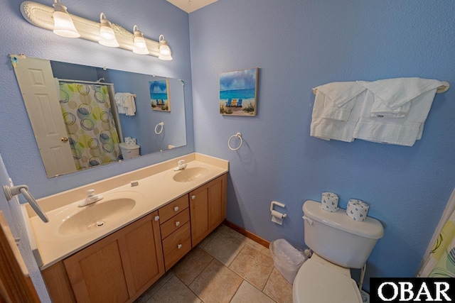 full bathroom with toilet, double vanity, a sink, and baseboards