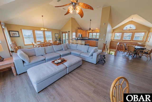 living area featuring high vaulted ceiling, a wealth of natural light, visible vents, wood finished floors, and ceiling fan with notable chandelier