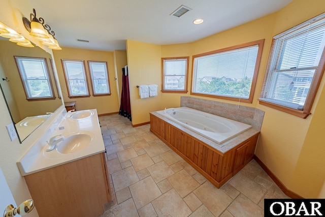 full bath featuring baseboards, visible vents, a whirlpool tub, and a sink