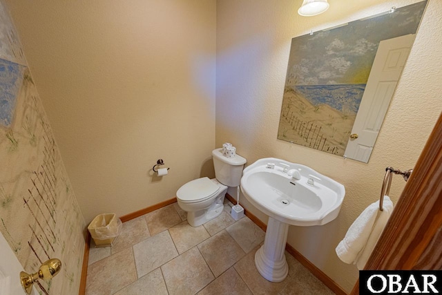 half bathroom with baseboards and toilet