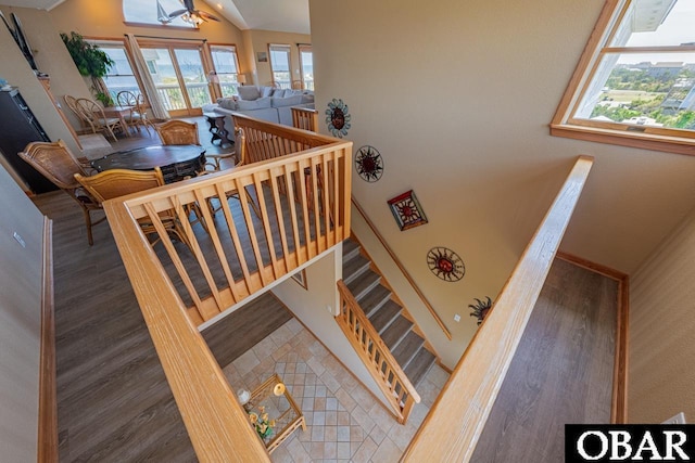 staircase with lofted ceiling, wood finished floors, and plenty of natural light