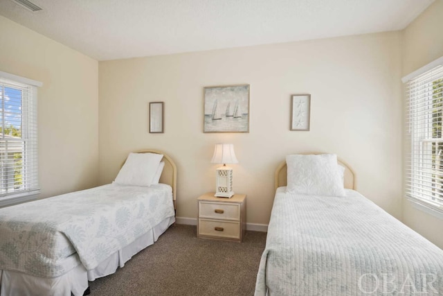 bedroom with dark colored carpet, visible vents, and baseboards