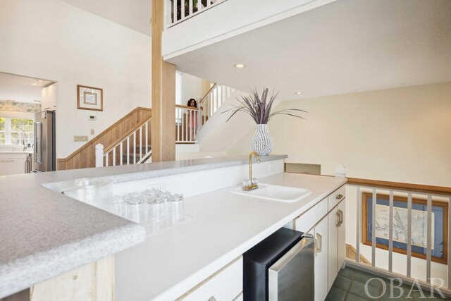 kitchen featuring light countertops, white cabinetry, high quality fridge, a sink, and fridge