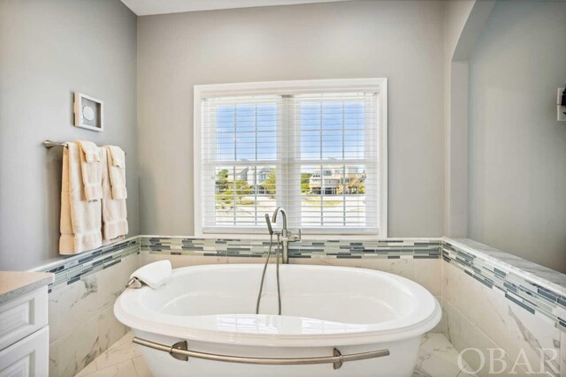 full bath featuring marble finish floor, vanity, and tile walls