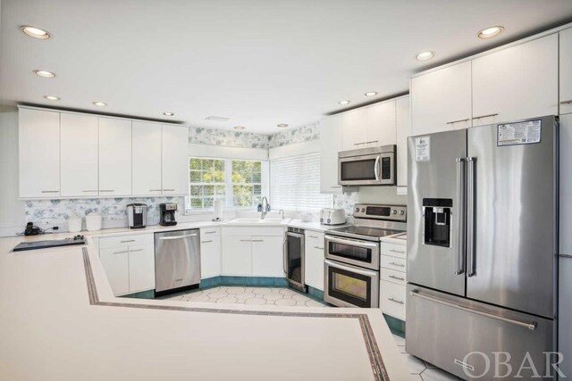 kitchen featuring stainless steel appliances, light countertops, white cabinetry, a sink, and recessed lighting