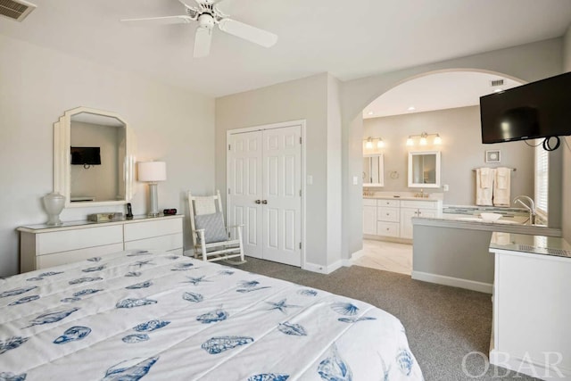 bedroom featuring visible vents, arched walkways, connected bathroom, light colored carpet, and a closet