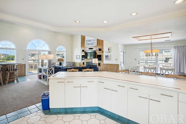 kitchen with a peninsula, white cabinetry, open floor plan, hanging light fixtures, and light countertops