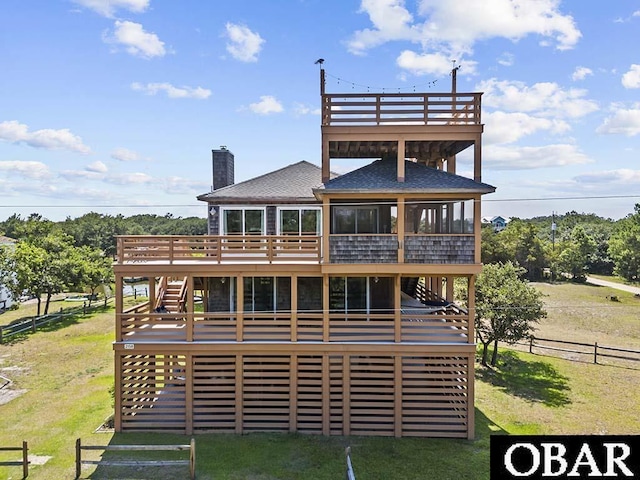 rear view of property featuring a deck, fence, a yard, and a sunroom