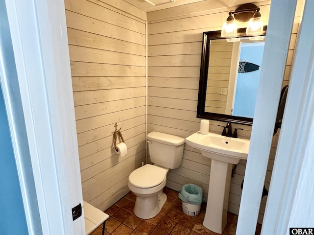 half bath with toilet and wood walls