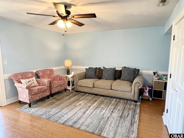living room with visible vents, a ceiling fan, and wood finished floors