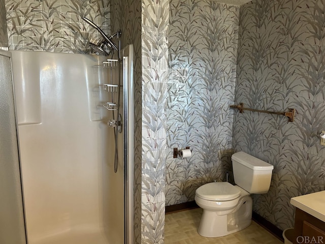 bathroom with vanity, a shower stall, toilet, and wallpapered walls