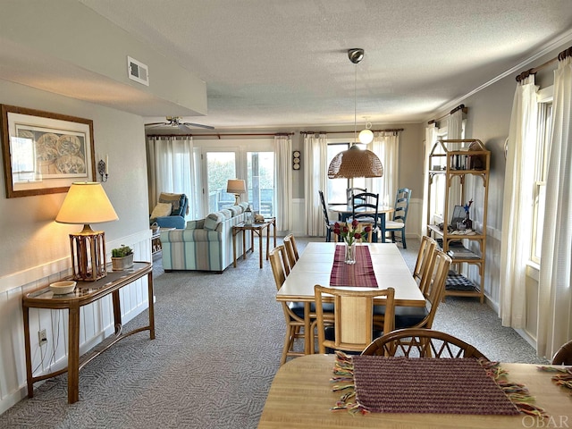 dining area featuring light colored carpet, visible vents, ornamental molding, ceiling fan, and a textured ceiling