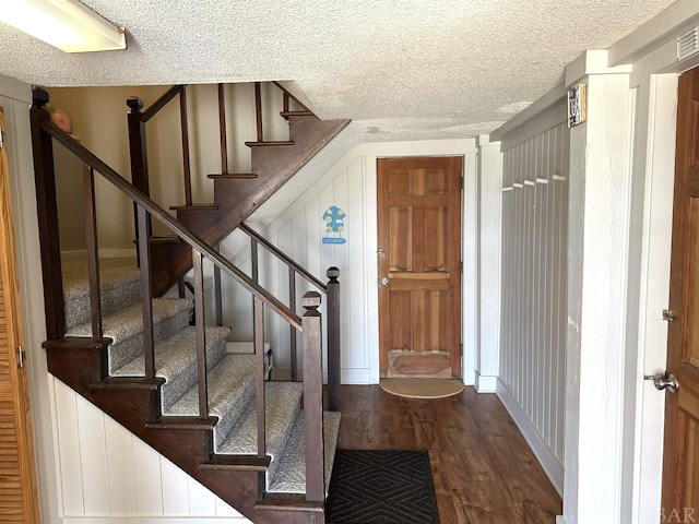 entryway featuring stairway, dark wood finished floors, and a textured ceiling