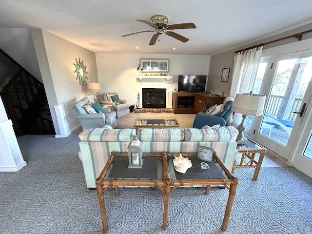 living area with carpet, a ceiling fan, and a glass covered fireplace