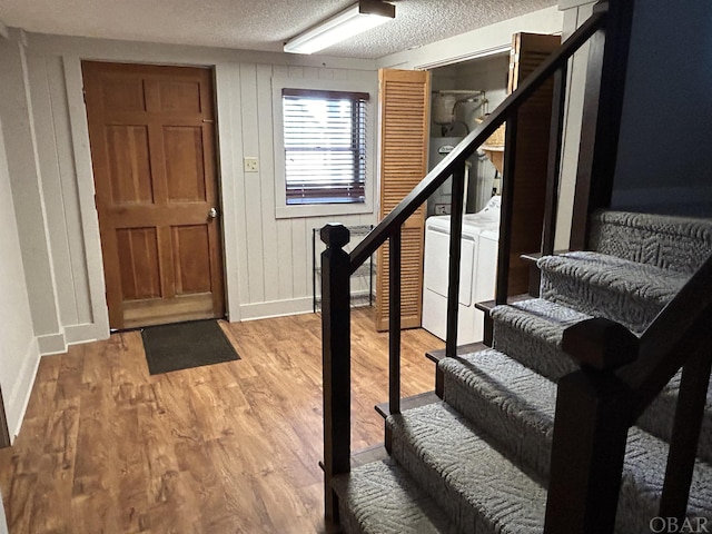 foyer entrance with baseboards, stairs, a textured ceiling, light wood-type flooring, and separate washer and dryer