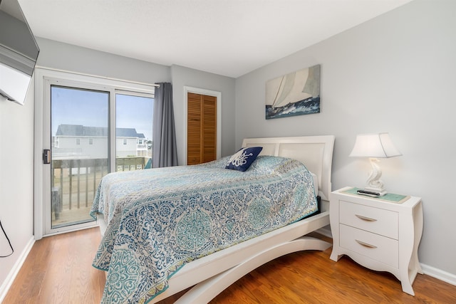 bedroom featuring access to outside, wood finished floors, and baseboards