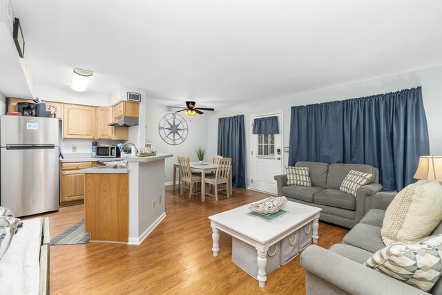 living area featuring light wood finished floors, ceiling fan, visible vents, and baseboards