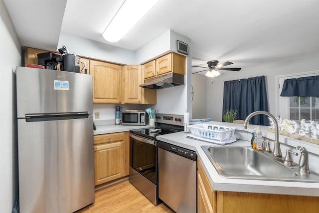 kitchen with stainless steel appliances, light countertops, a sink, and under cabinet range hood