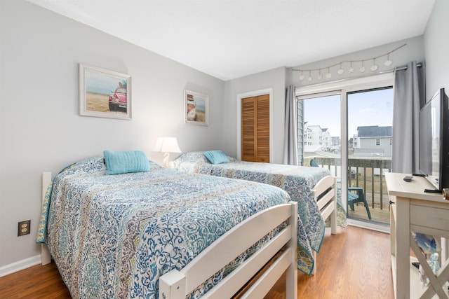 bedroom featuring access to outside, a closet, wood finished floors, and baseboards