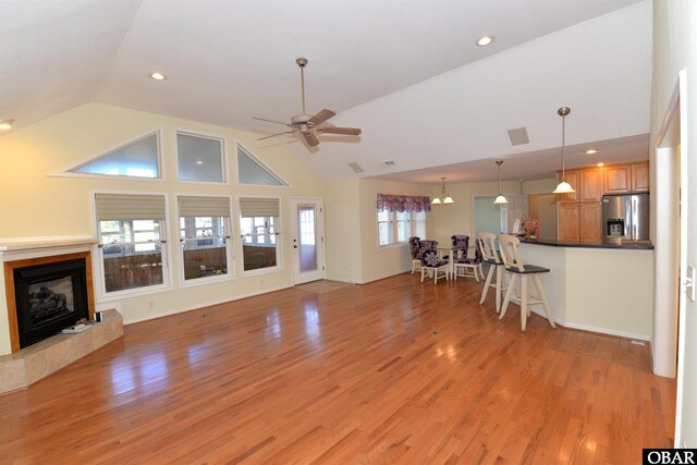 unfurnished living room with ceiling fan, light wood-style flooring, a fireplace with raised hearth, and recessed lighting