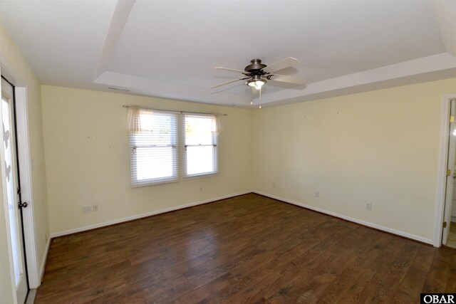 unfurnished room with a tray ceiling, baseboards, ceiling fan, and hardwood / wood-style floors