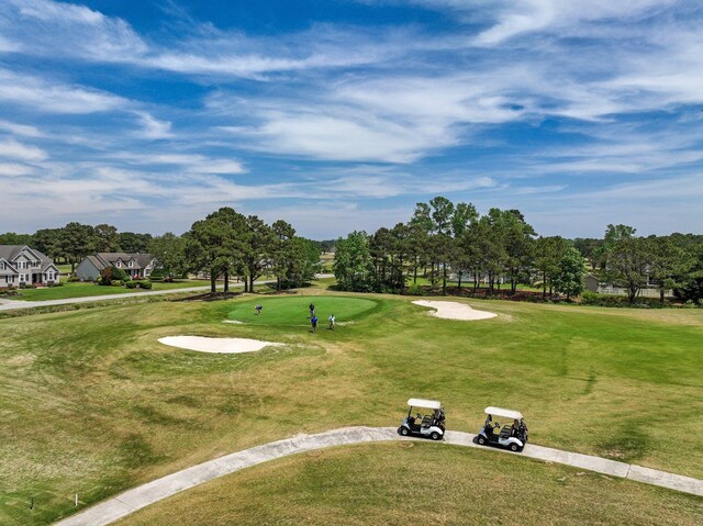 view of home's community with view of golf course and a lawn