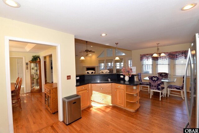 kitchen with dark countertops, light wood-style flooring, freestanding refrigerator, hanging light fixtures, and open shelves