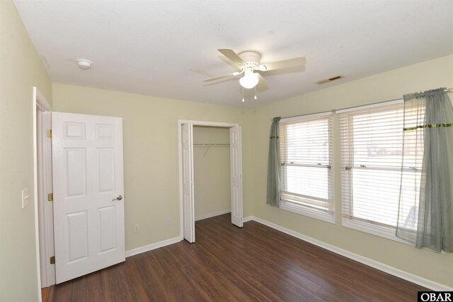 unfurnished bedroom with a ceiling fan, visible vents, baseboards, a closet, and dark wood-style floors