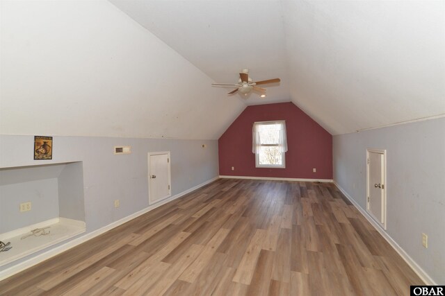 bonus room with lofted ceiling, light wood-style flooring, baseboards, and a ceiling fan