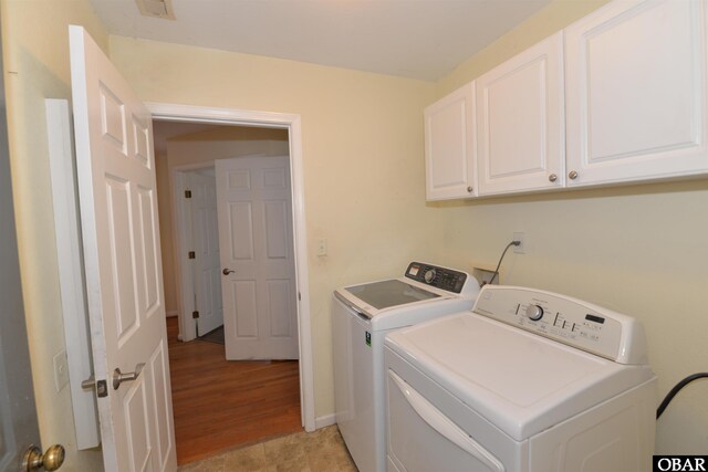 washroom with visible vents, cabinet space, washer and clothes dryer, and baseboards