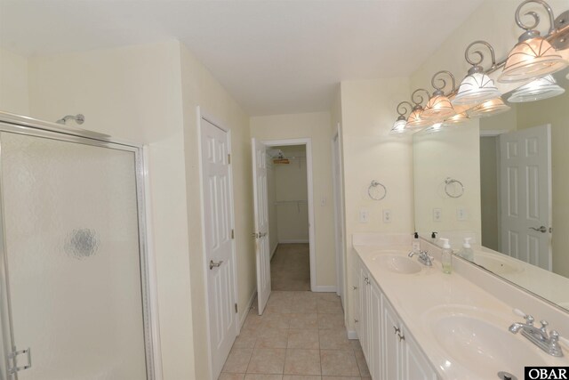 full bathroom with double vanity, a stall shower, tile patterned flooring, and a sink