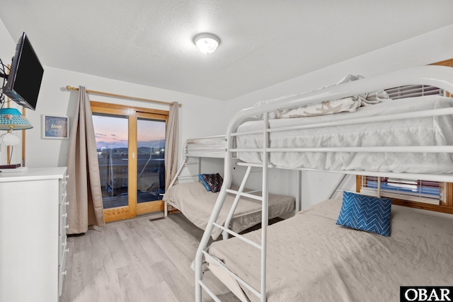 bedroom with a textured ceiling, wood finished floors, and access to exterior