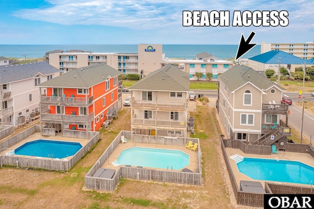 pool with a water view, a fenced backyard, and a residential view