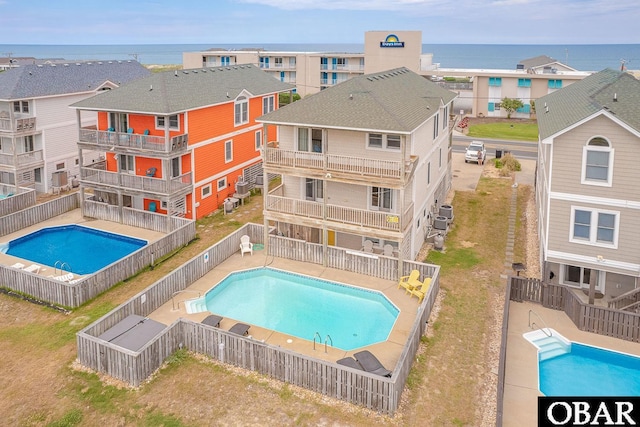 pool featuring a residential view, a patio area, a fenced backyard, and a water view